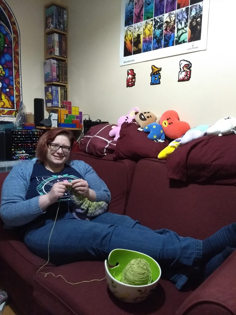 Emily Anne Davies knitting on her couch.