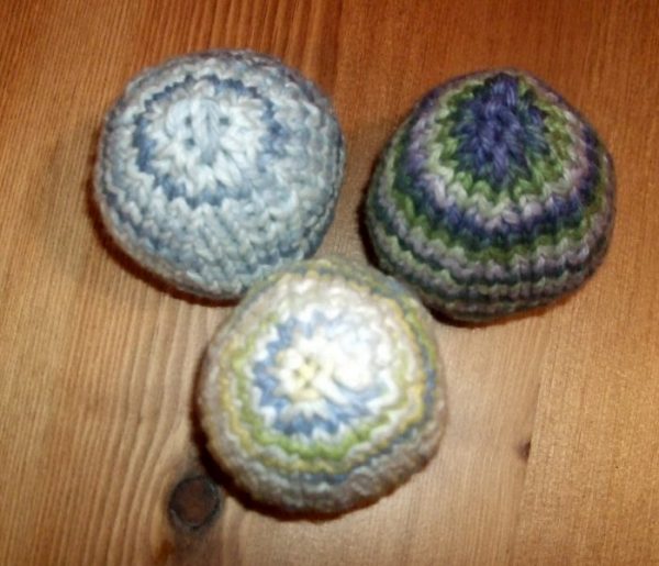 Three hand-knitted easter eggs made with self-striping yarn.