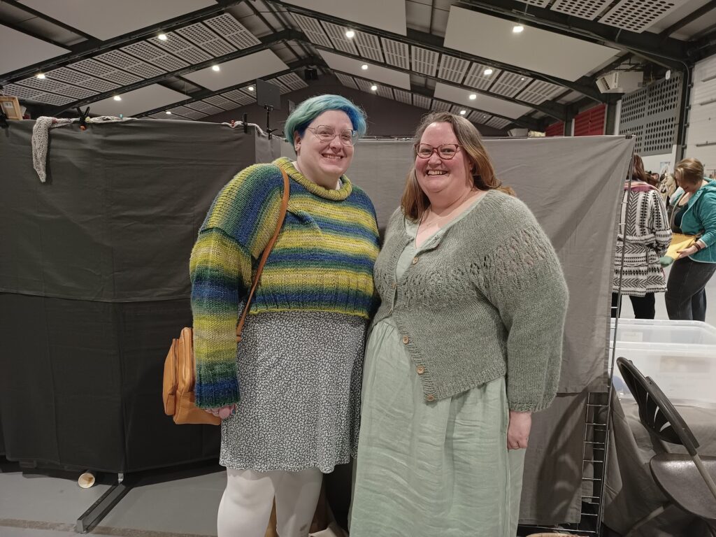 A photo of me and Victoria at the East Anglia Yarn Festival! I dyed my hair blue, green and yellow to match my jumper, which Victoria designed. Victoria is wearing a pastel green linen dress topped with her own design, a pastel green lace cardigan.